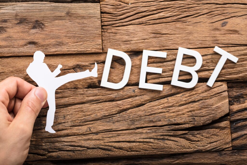 outline of person kicking the word "debt" to illustrate concept of paying off debt